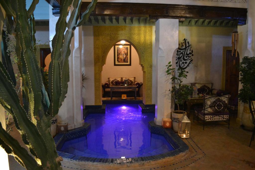 Riad Bayti في مراكش: منزل به مسبح ازرق كبير في غرفة بها صبار