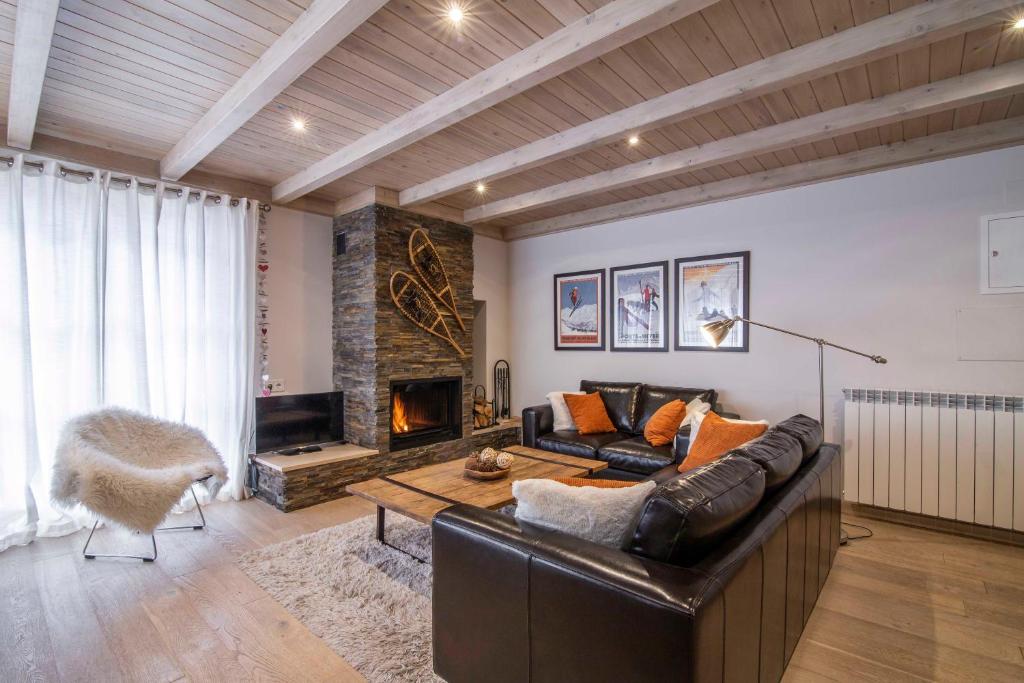 a living room with a leather couch and a fireplace at FLOC DE NEU de Alma de Nieve in Baqueira-Beret