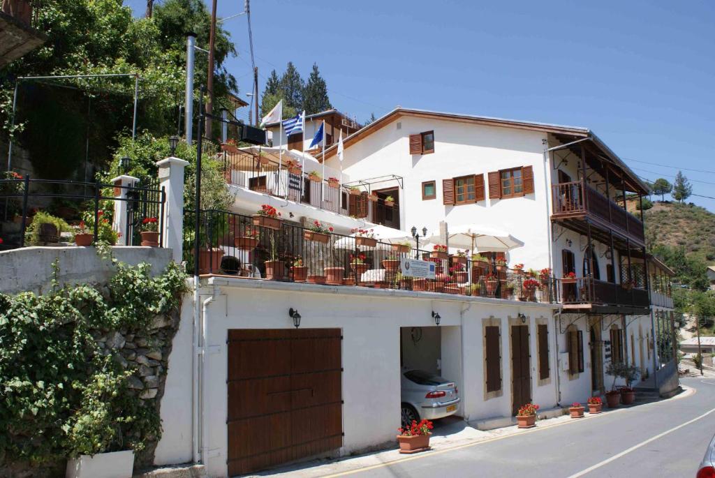 a white house with a balcony on a street at ATRATSA Mountain Suites in Kalopanayiotis