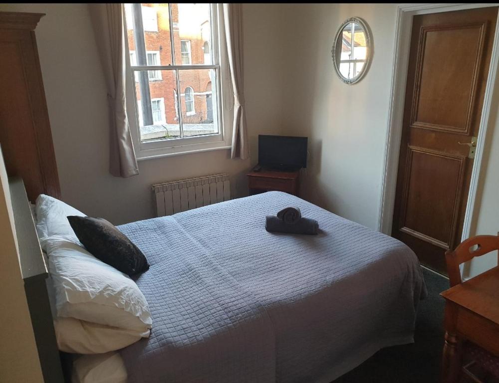 a bedroom with a bed with a hat on it at The Olde Swan Hotel in Chertsey