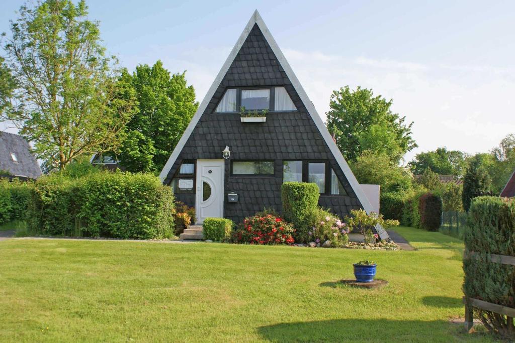 a black house with a pointed roof on a yard at Zeltdachhaus _ strandnah _ extra T in Damp