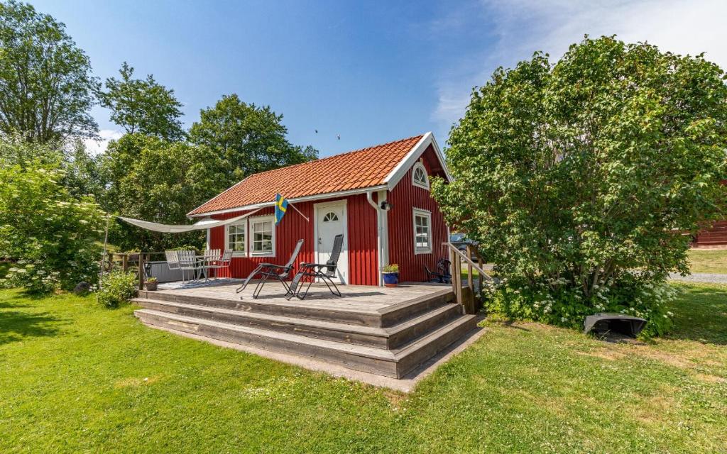 una casa roja con terraza de madera en el patio en Fårbo, en Gissebo