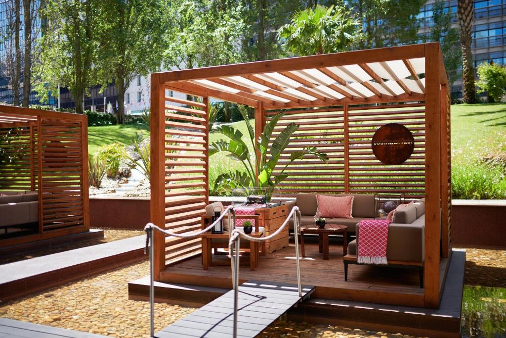 a wooden pergola with a couch and chairs on a patio at Corinthia Lisbon in Lisbon