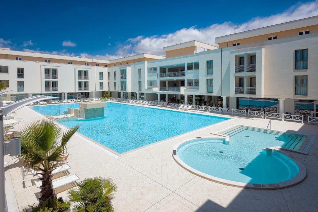 a large swimming pool in front of a large building at Hotel Terme Marine Leopoldo II TERME & SPA in Marina di Grosseto