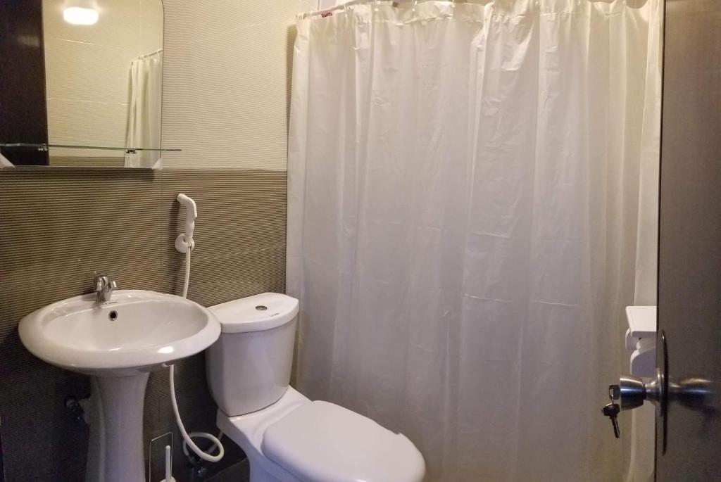 a bathroom with a white toilet and a sink at JSK Apartment in Bacoor