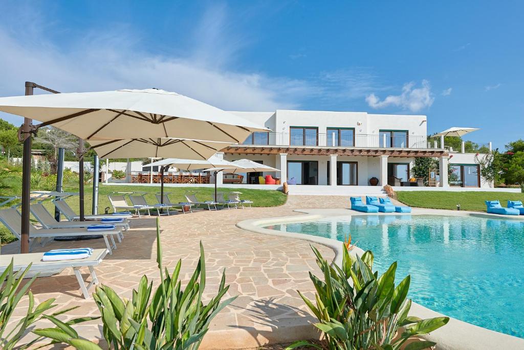 ein Haus mit einem Pool mit Stühlen und einem Sonnenschirm in der Unterkunft Fiframar in San Jose de sa Talaia