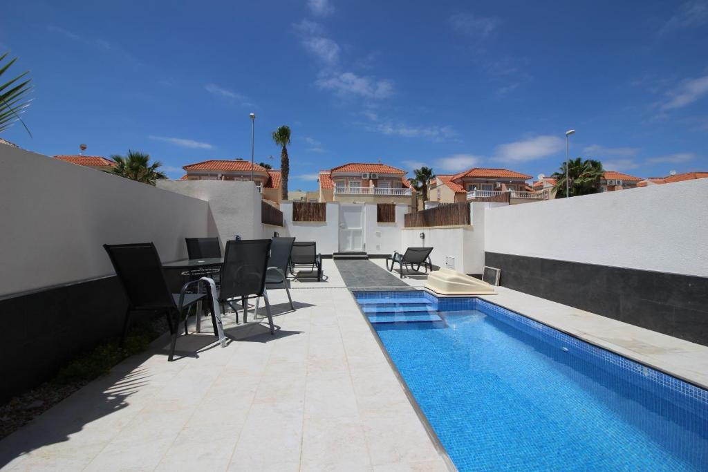 un patio con piscina, sillas y mesa en Villa La Zenia Boulevard 36 en Playa Flamenca