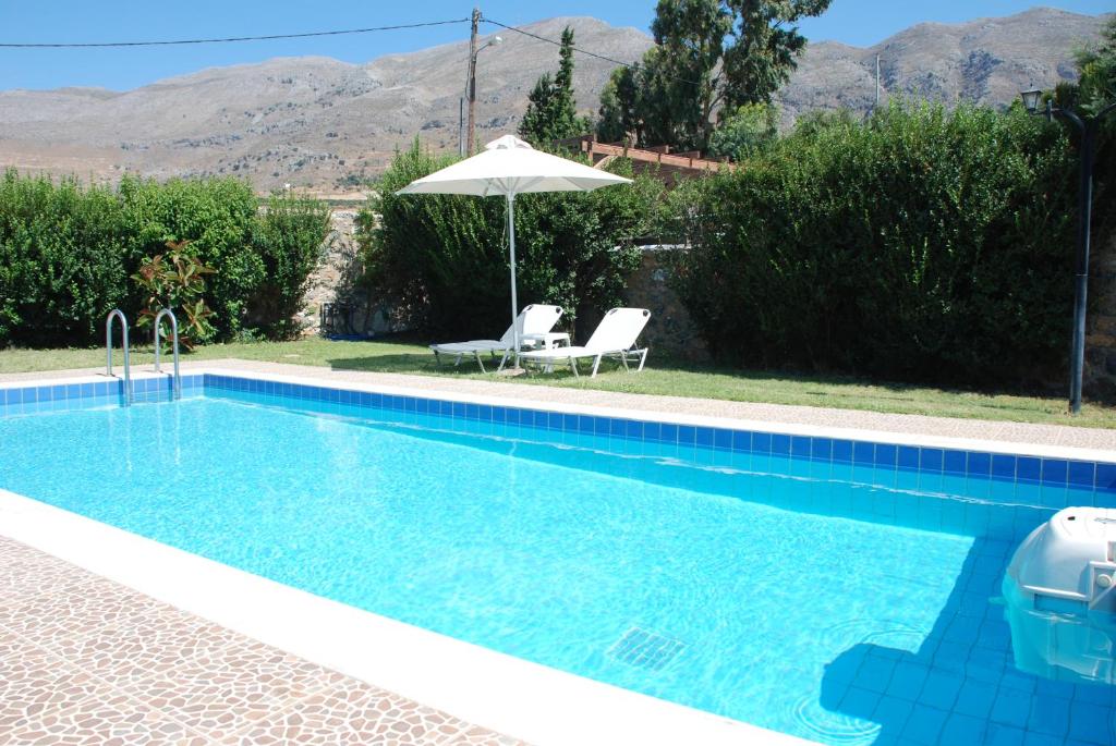 una piscina azul con sombrilla y 2 sillas en Villa with a pool in Lefkogia en Lefkogeia