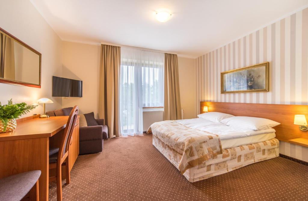 a hotel room with a bed and a desk at Astra Dziwnówek Dom Gościnny in Dziwnówek