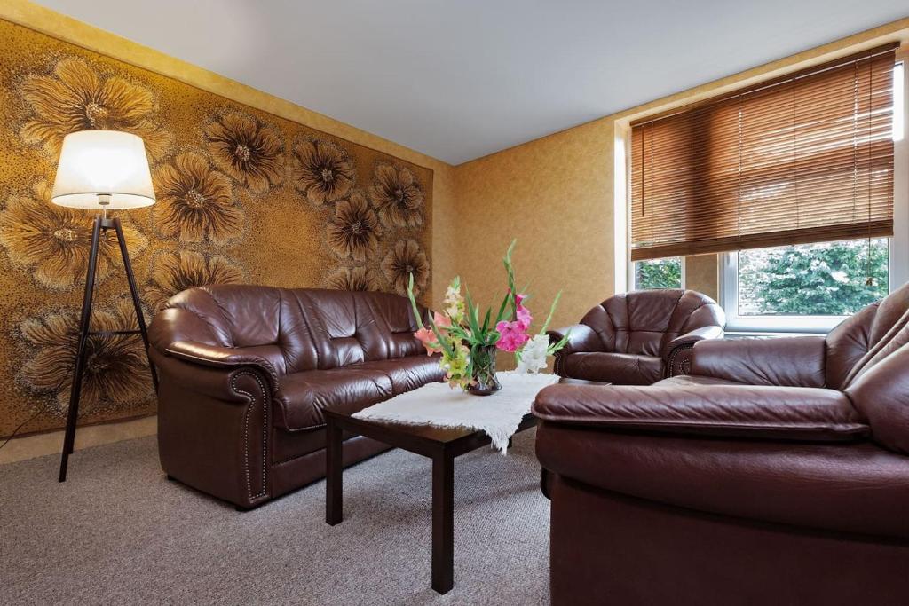 a living room with two leather chairs and a table at Second Floor Apartament in Liepāja
