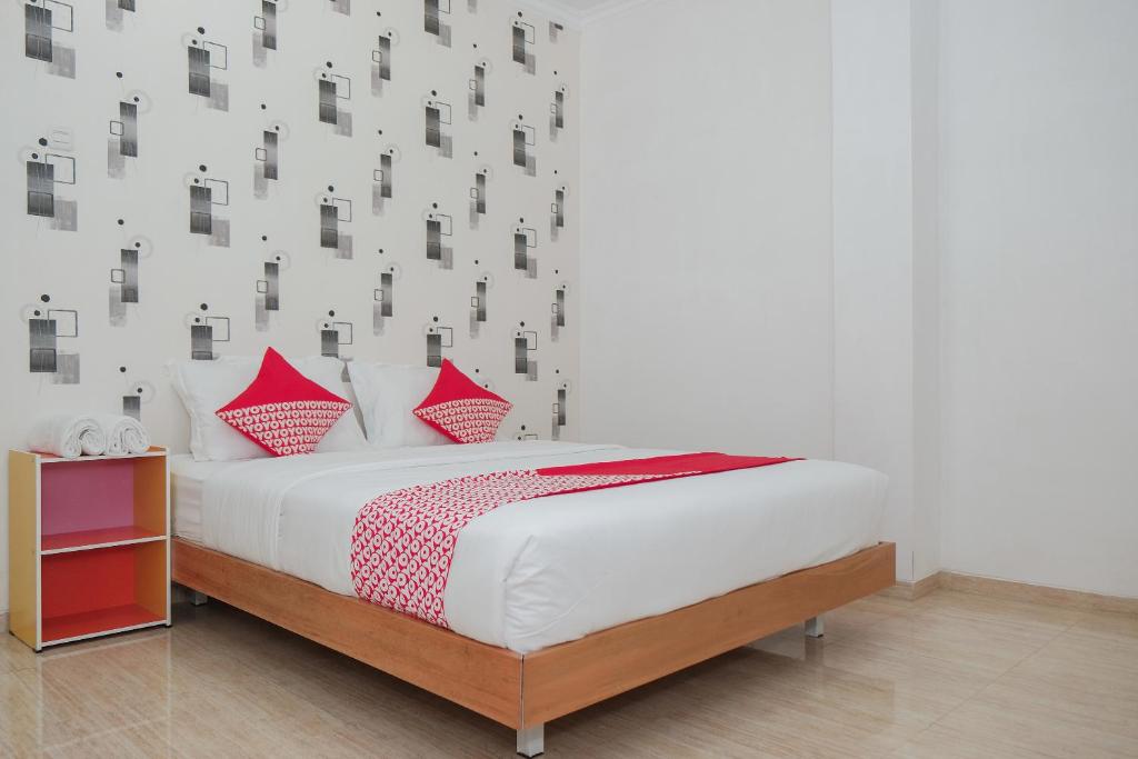 1 dormitorio con 1 cama con almohadas rojas en OYO 1454 111 Residence en Batu