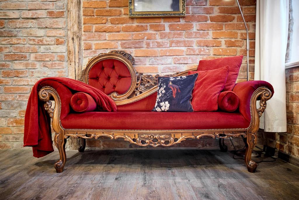 a red couch sitting in front of a brick wall at Strohhutmanufaktur in Dresden