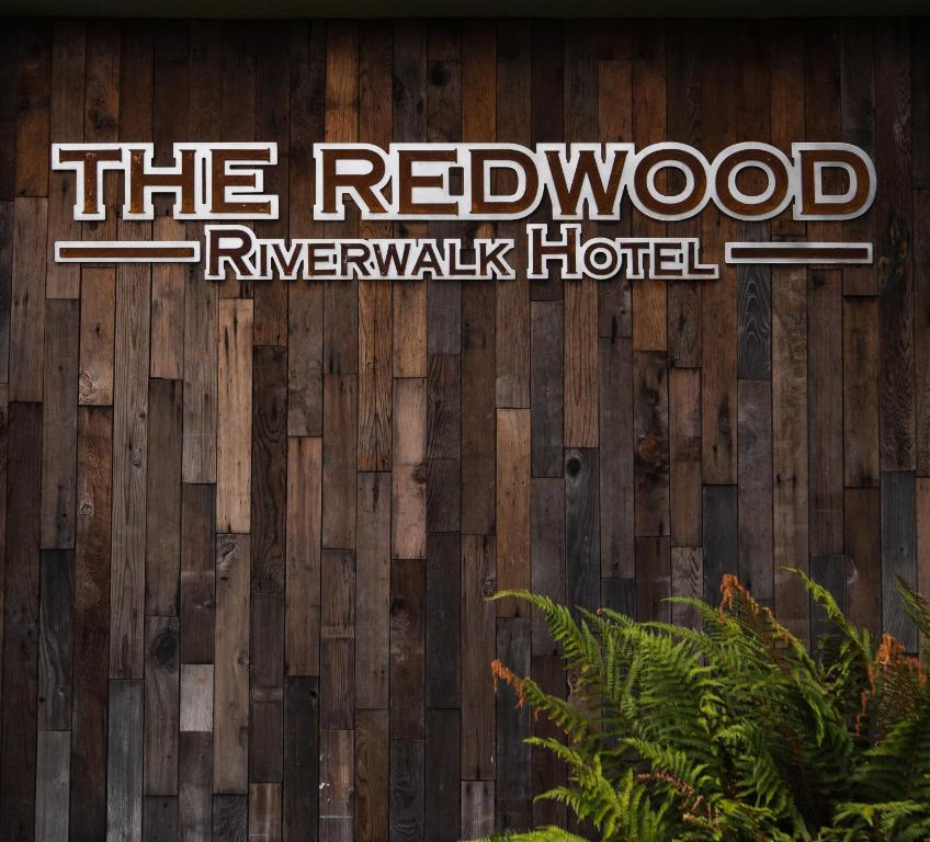 a sign for the redwood rangerwalk hotel on a wooden wall at The Redwood Riverwalk, a boutique hotel in Fortuna