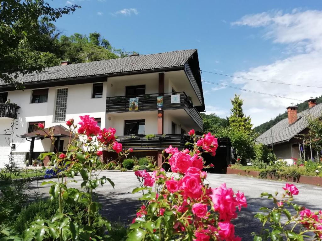 una casa con flores rosas delante de ella en Apartment Panorama en Bohinjska Bela