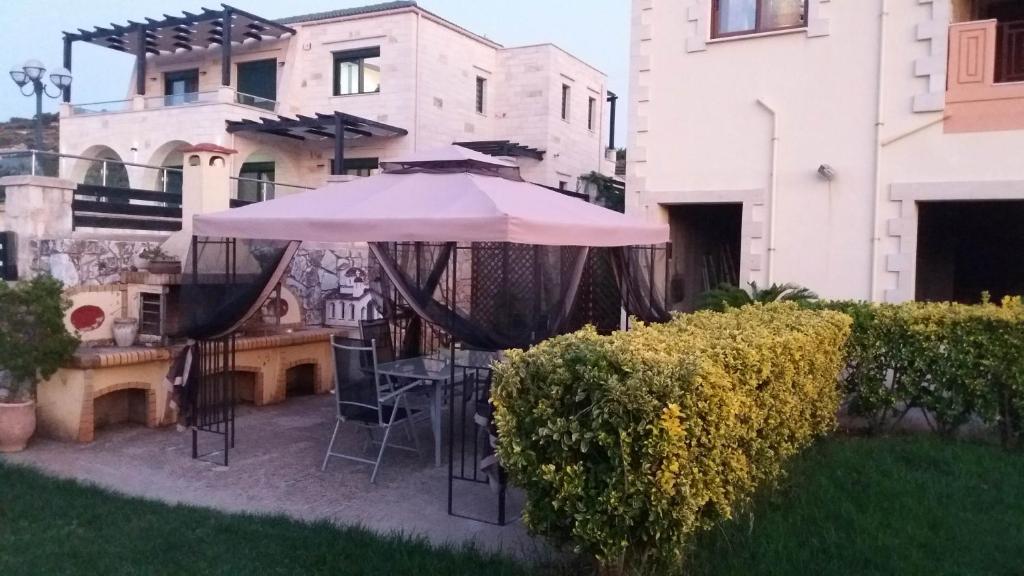 a patio with an umbrella and chairs in a yard at Nikos Studio in Kalyves
