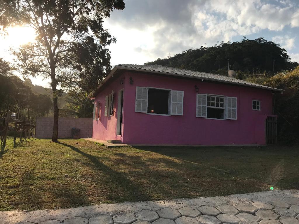 una casa rosa seduta in cima a un cortile di Casa Ibitipoca a Conceição da Ibitipoca
