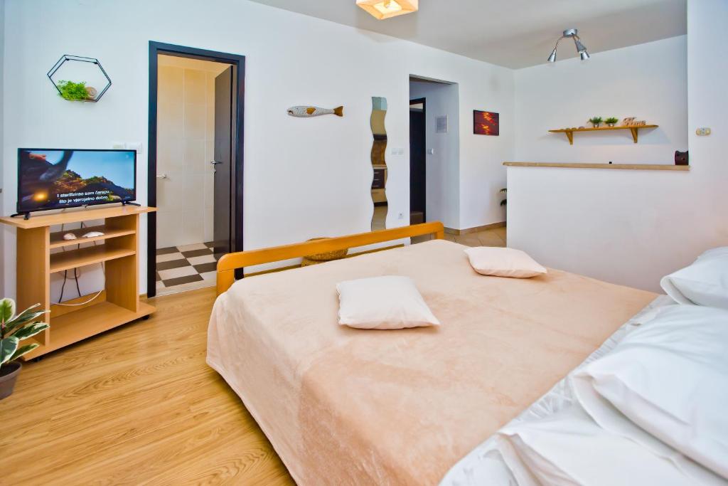 a bedroom with a large bed and a television at HVAR apartments 8 min to the beach in Hvar