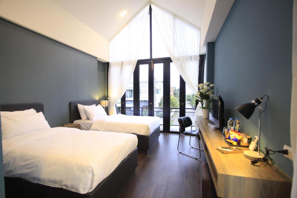 a bedroom with two beds and a desk and a window at The Nichehome Waterside Living in Chiang Mai
