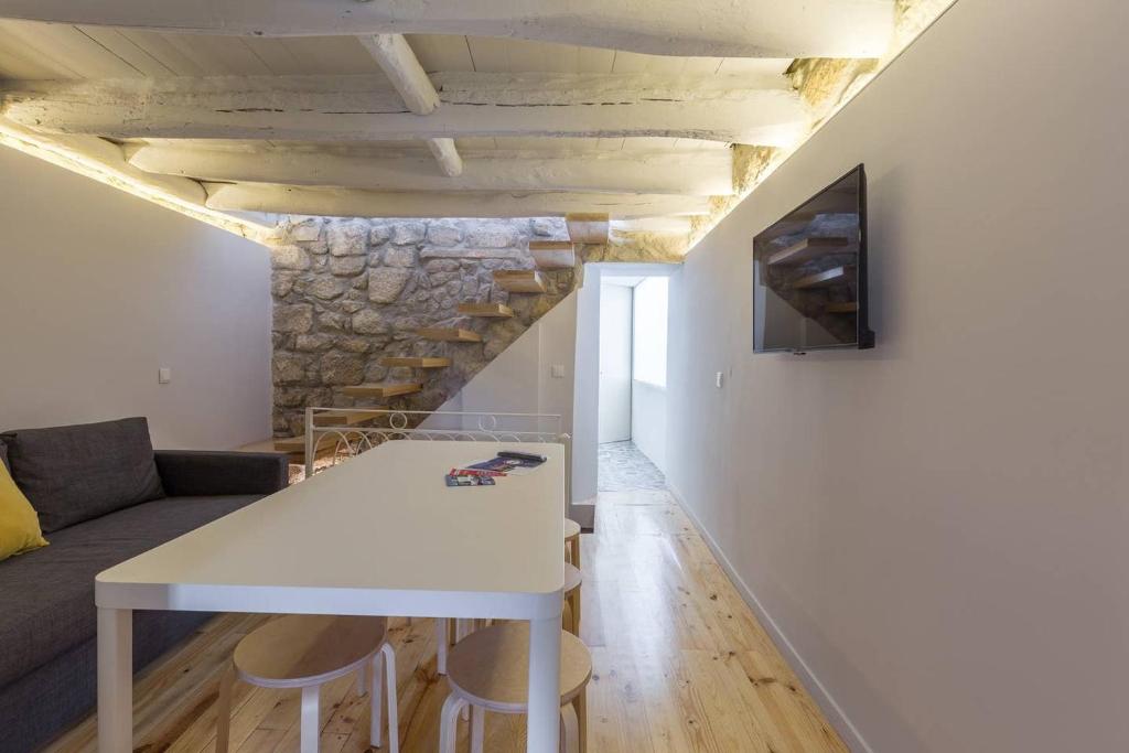 een woonkamer met een witte tafel en een stenen muur bij Heart Of The Porto in Porto