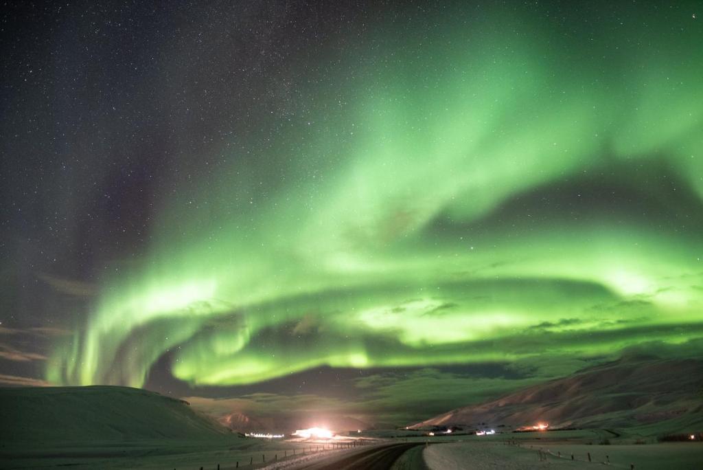 an aurora in the sky over a snowy field at Grýtubakki I in Grenivík