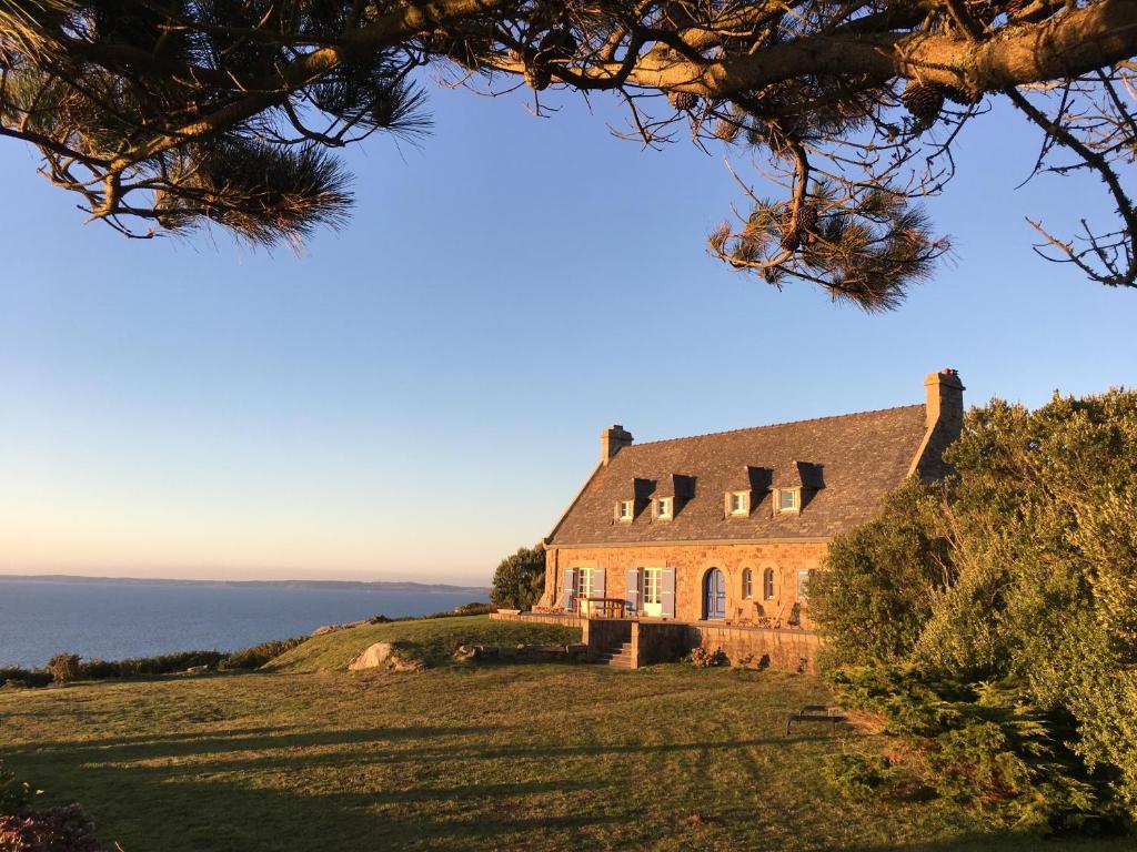 a house on a hill with the ocean in the background at Kerloulou in Poullan-sur-Mer