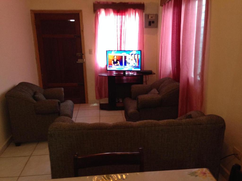 a living room with a couch and two chairs and a television at Elizabeth Enchantments in La Ceiba