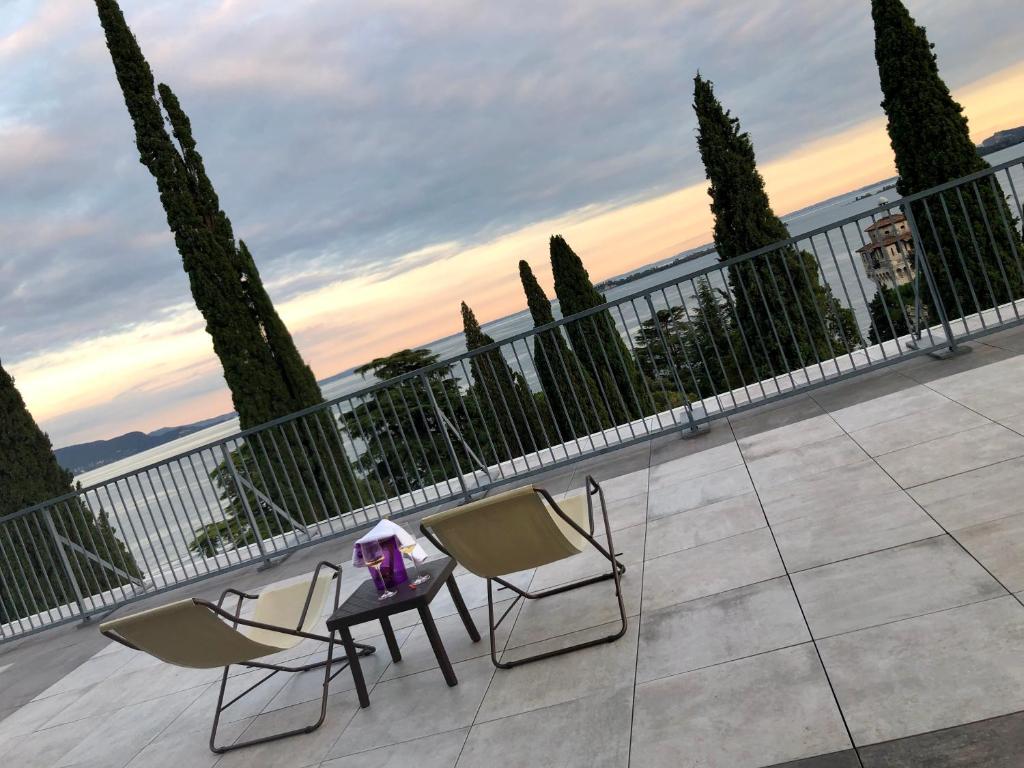 2 sedie e un tavolo sul balcone con alberi di Residence Villa Alba a Gardone Riviera