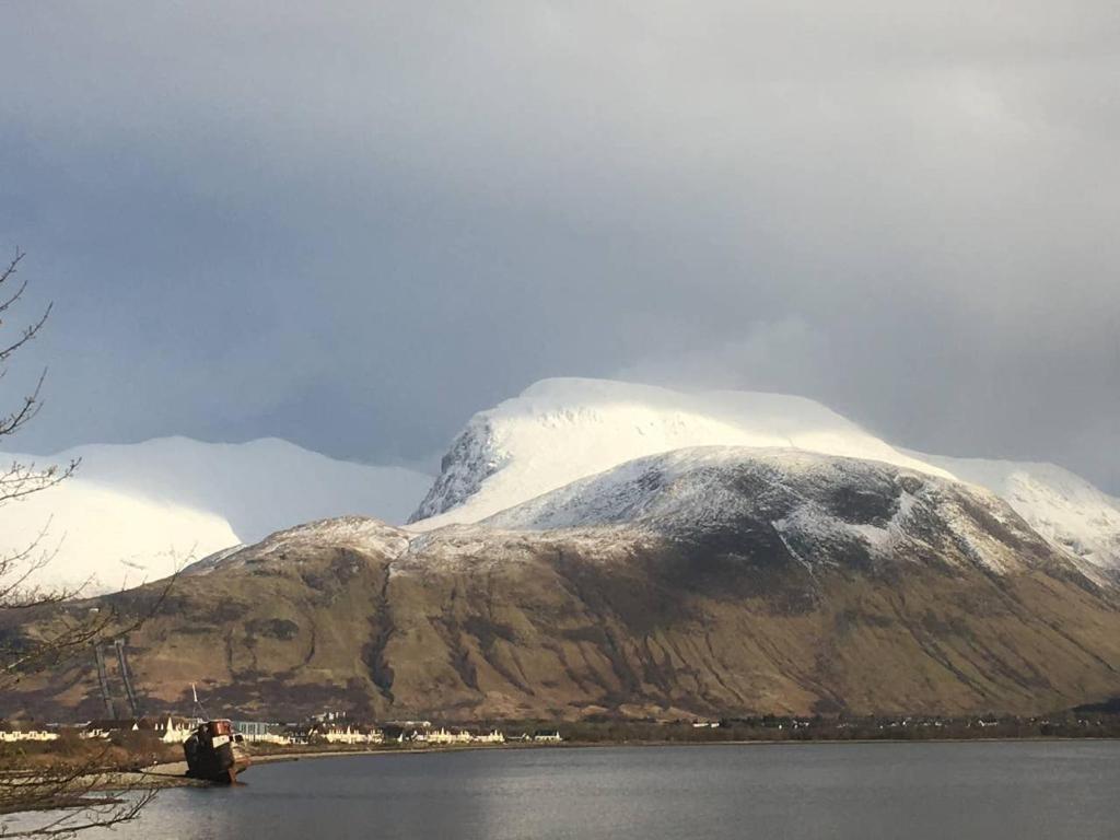 a snow covered mountain next to a body of water at situated at the heart of fort william in Fort William