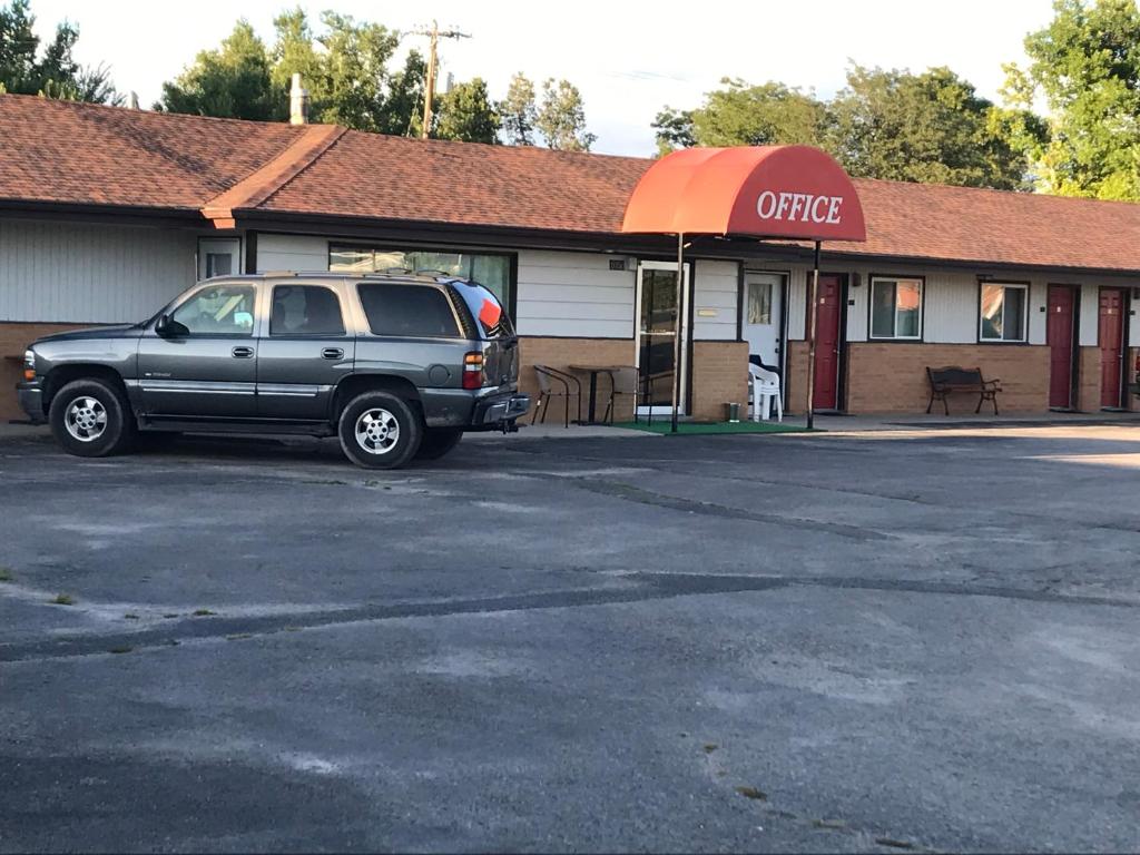 Un todoterreno estacionado en un estacionamiento frente a una cafetería en Motel Grand en Chadron