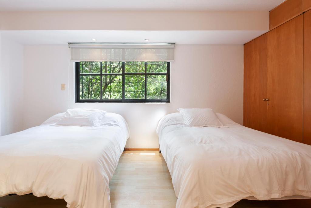 2 Betten in einem Zimmer mit Fenster in der Unterkunft Lovely apartment Ahuehuetes in Mexiko-Stadt