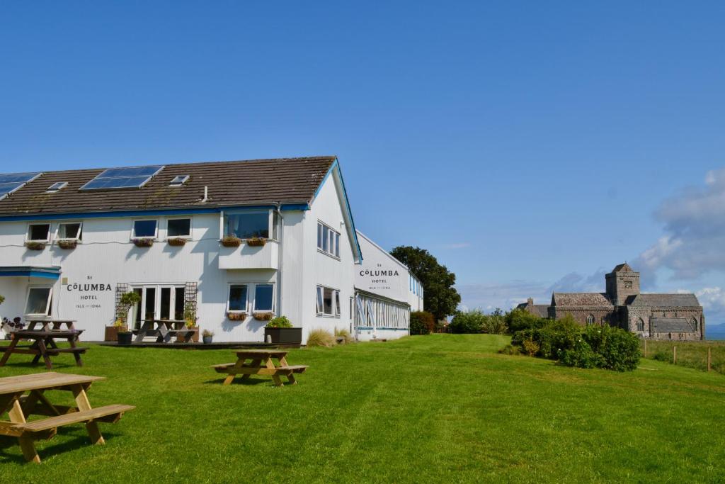 a large white building with picnic tables in the grass at St Columba Hotel in Iona