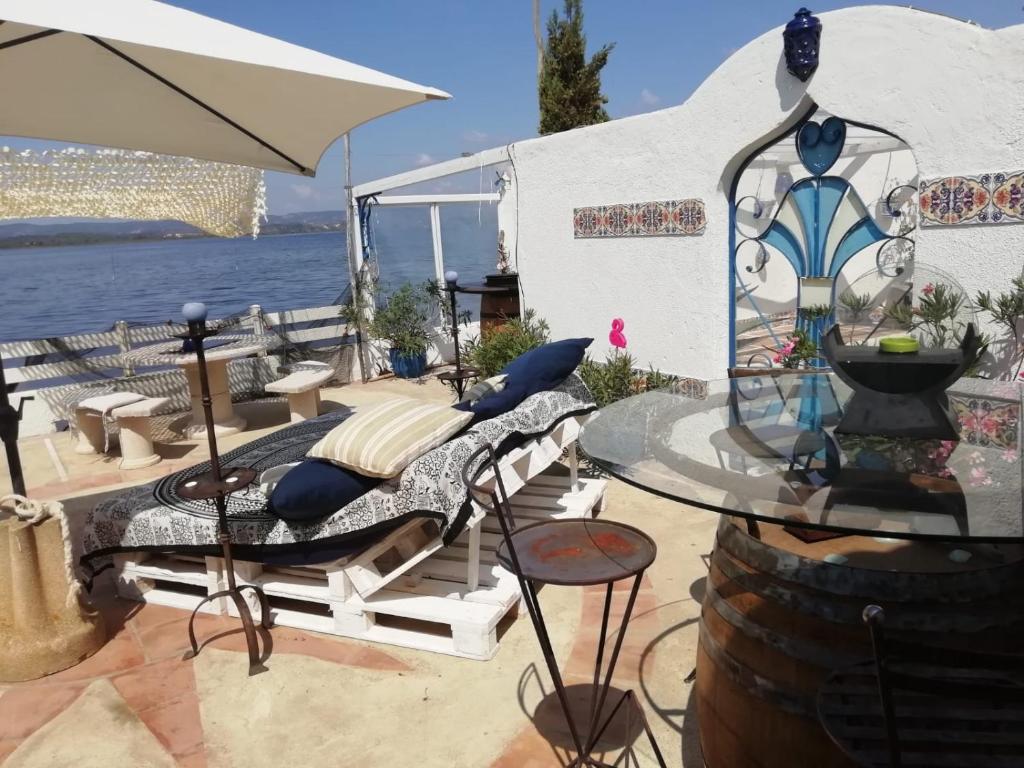 ein Bett auf einer Terrasse mit einem Tisch und einem Sonnenschirm in der Unterkunft Maison de pecheur in Sigean