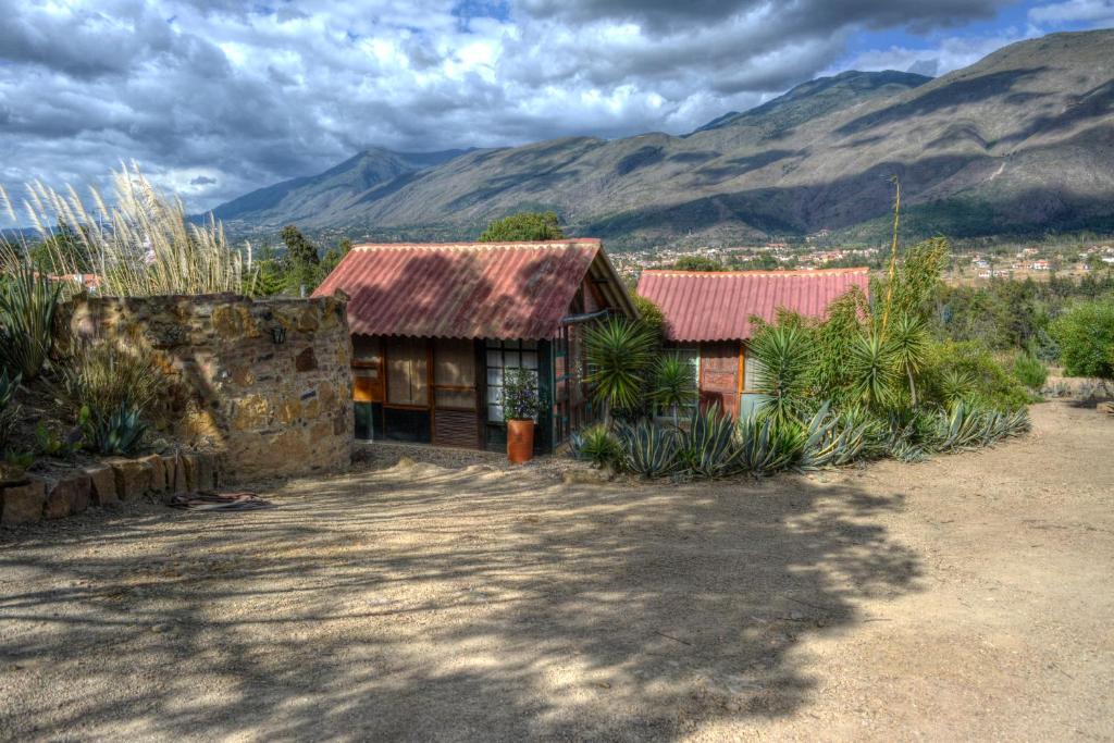 a house with a red roof with mountains in the background at The Little Glass House in Villa de Leyva