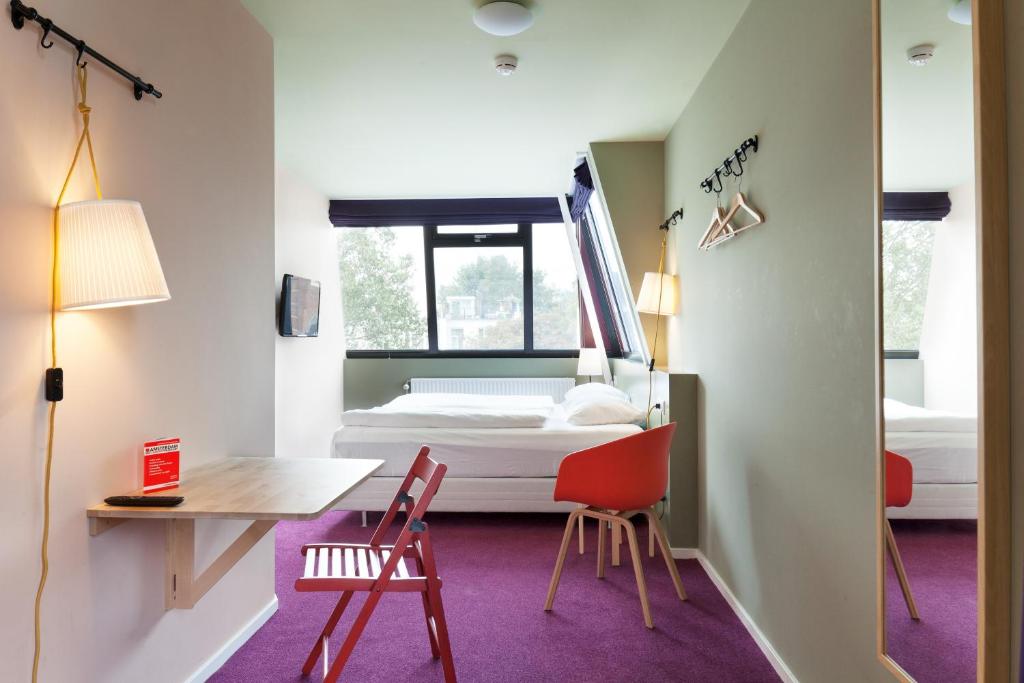 een kamer met een bed, een bureau en stoelen bij Hotel The Neighbour's Magnolia in Amsterdam