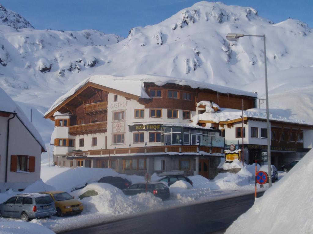 um grande edifício com carros estacionados na neve em Gasthof Valluga em Sankt Christoph am Arlberg