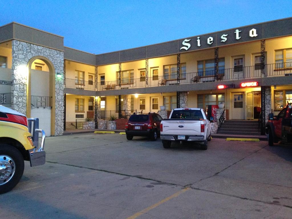 un edificio con coches estacionados en un estacionamiento en Siesta Motel, en Havre