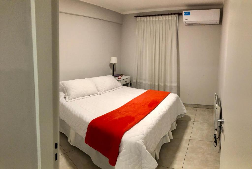 um quarto com uma cama com um cobertor vermelho e branco em Departamento - Edificio Costanera em San Salvador de Jujuy