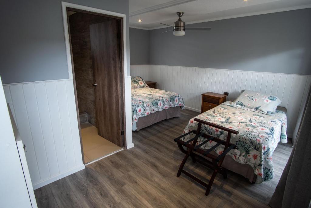 a small room with two beds and a chair in it at Inaki Uhi Hotel in Hanga Roa