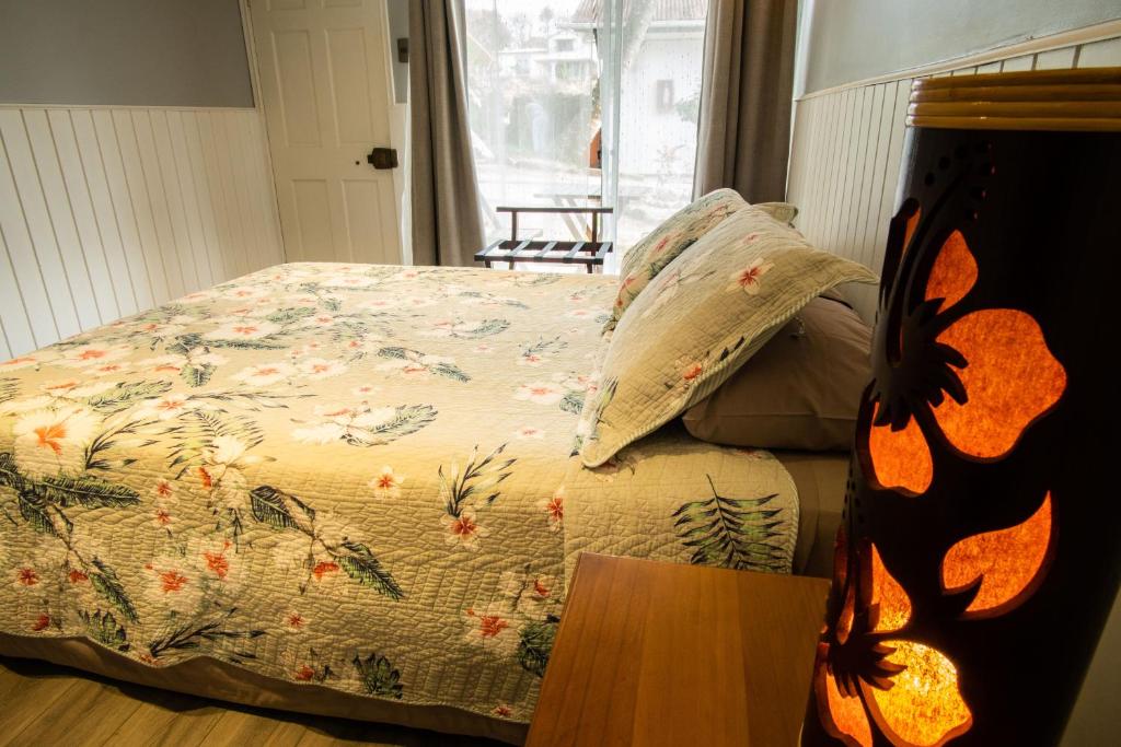 a bedroom with a bed with a floral comforter at Inaki Uhi Hotel in Hanga Roa