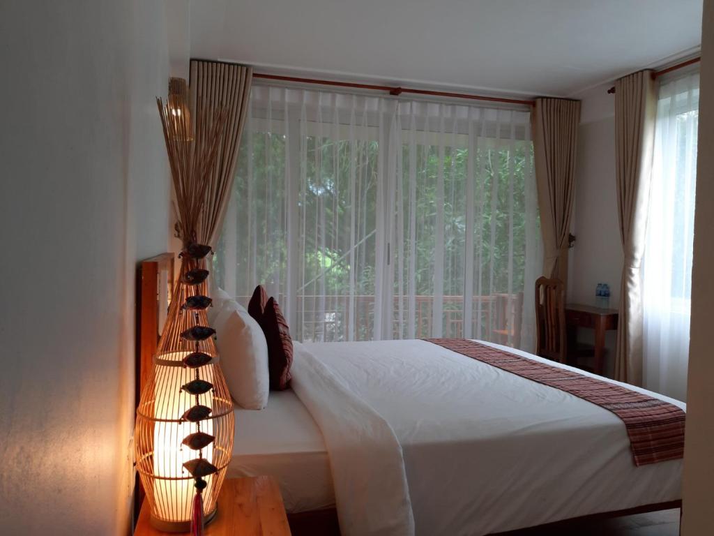 a bedroom with a bed and a large window at Mai Chau Dreams Homestay in Mai Chau