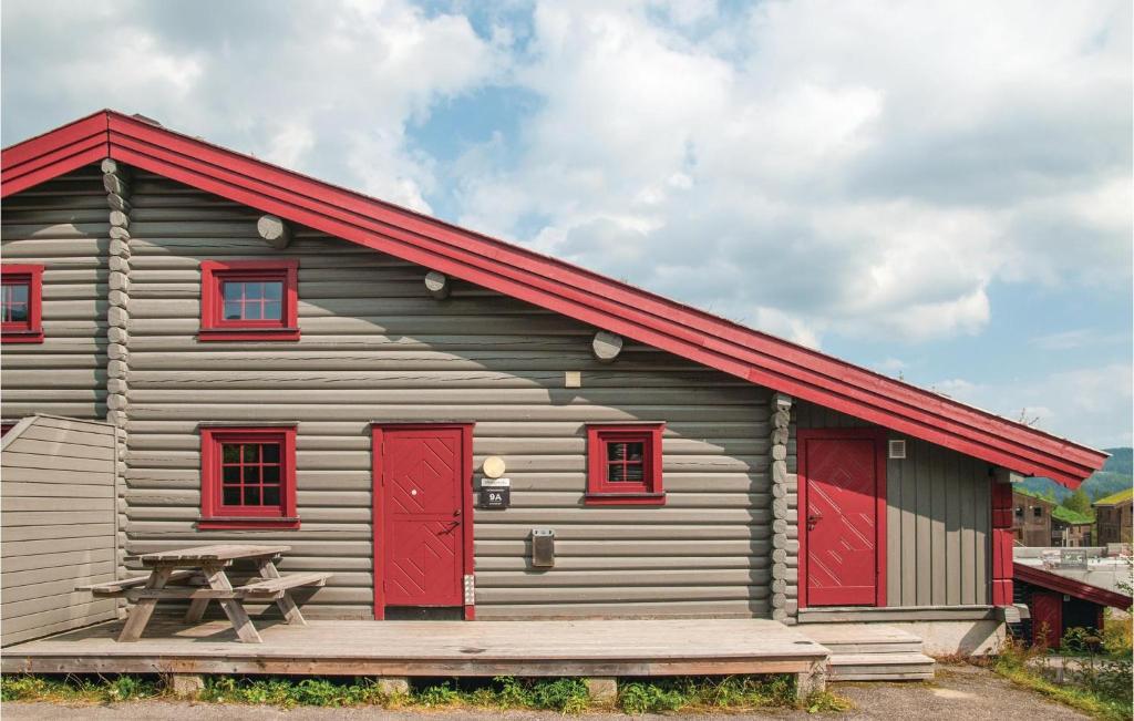 eine kleine Hütte mit roten Türen und einem Picknicktisch in der Unterkunft Cozy Apartment In Trysil With Sauna in Trysil