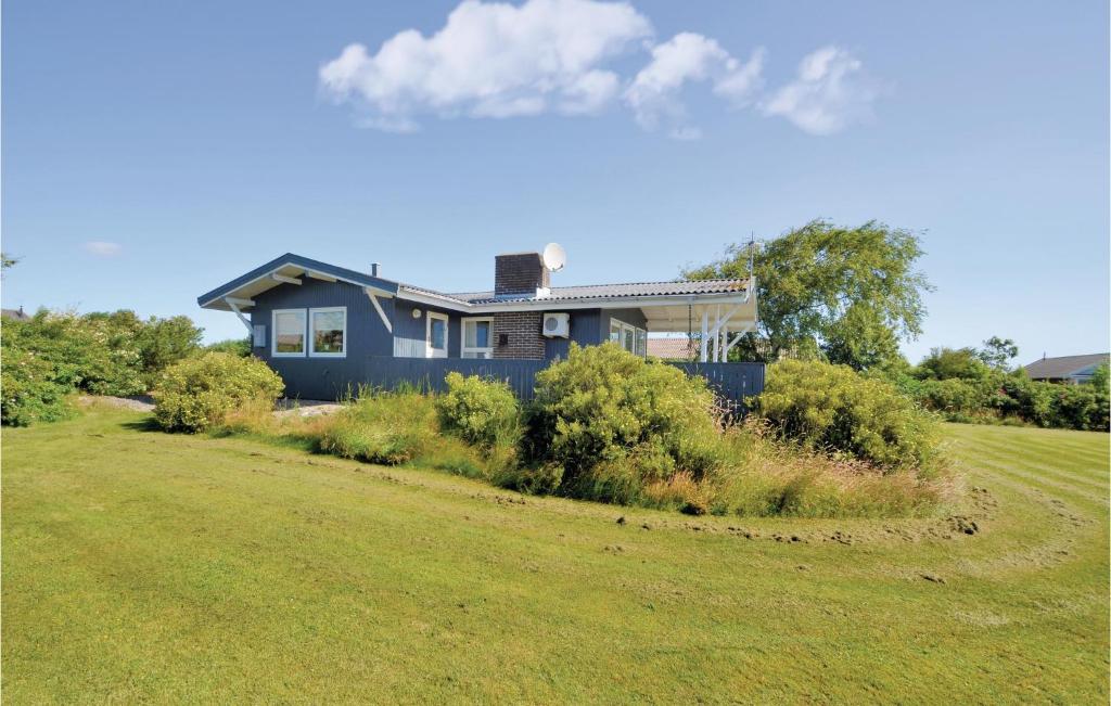 ein blaues Haus auf einem Feld mit einem Hof in der Unterkunft Lovely Home In Hurup Thy With House Sea View in Doverodde