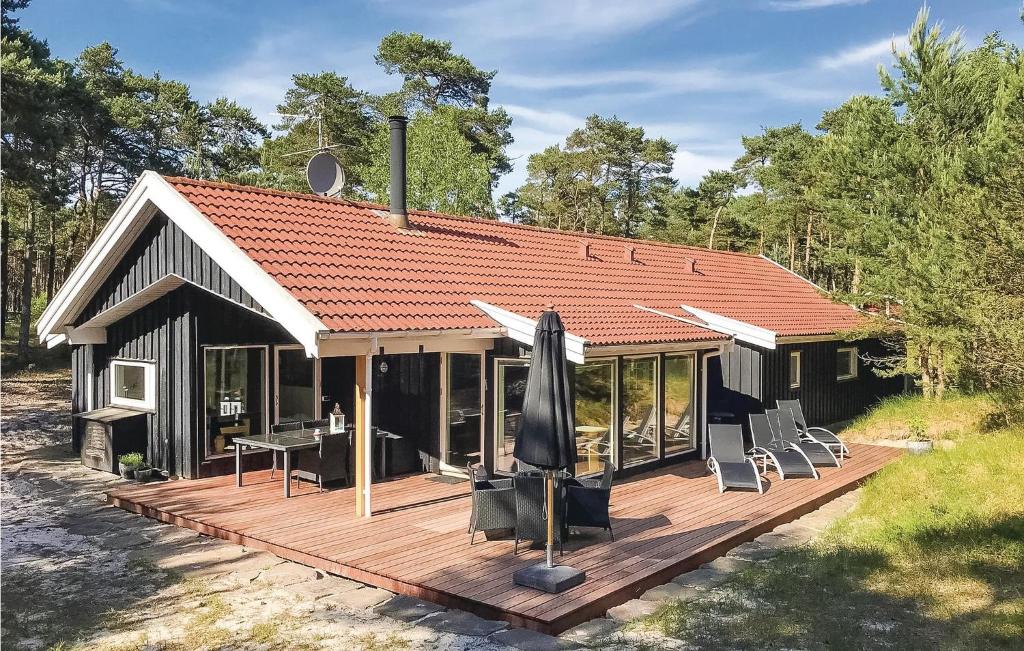 ein Haus mit einer Terrasse mit Stühlen und einem Sonnenschirm in der Unterkunft Four-Bedroom Holiday Home In Nexo in Vester Sømarken