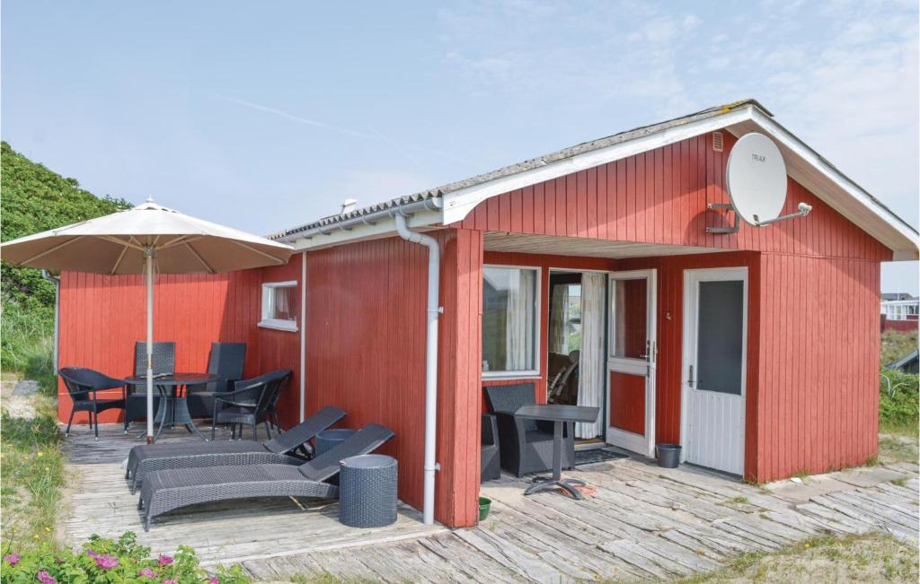 Casa roja con mesa, sillas y sombrilla en Awesome Home In Ringkbing With 2 Bedrooms, en Søndervig