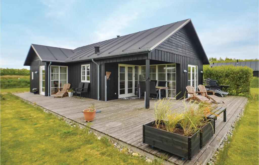 una casa negra con terraza de madera en un patio en Stunning Home In Nysted With Wifi, en Nysted