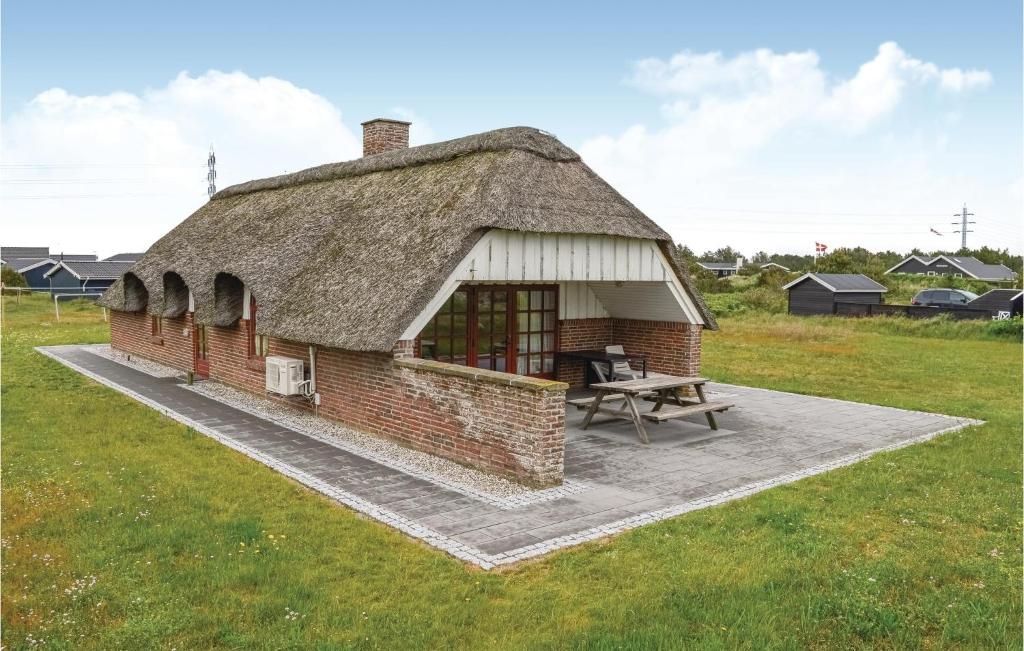 a small brick building with a picnic table in a field at Amazing Home In Ringkbing With Kitchen in Klegod