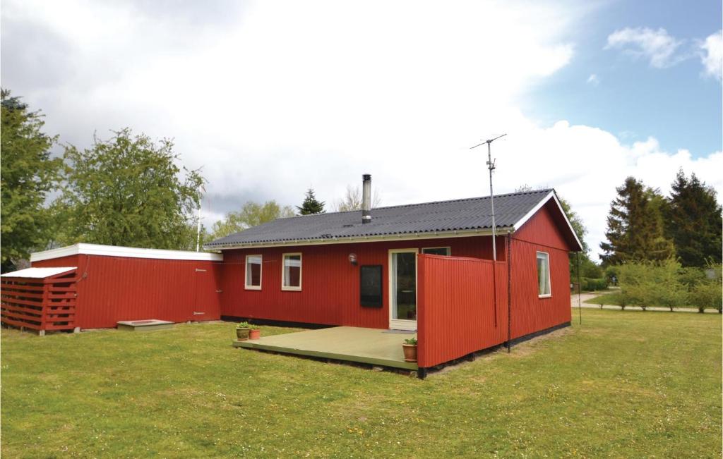 a red tiny house in a grassy field at Awesome Home In rsted With Kitchen in Kare