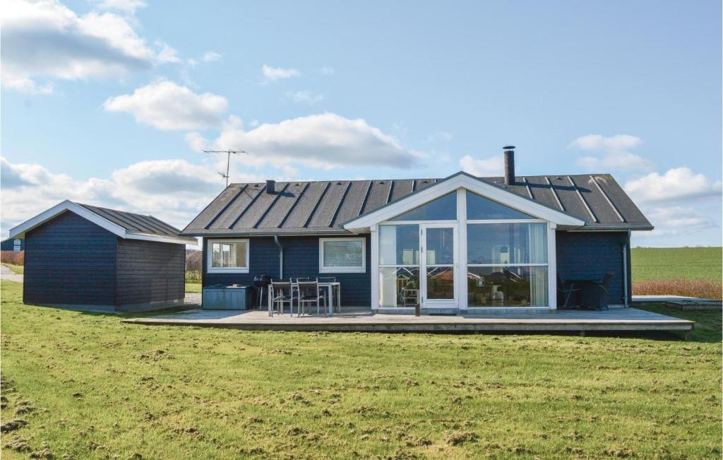 a blue house with a table and chairs in a field at Nice Home In Lemvig With 3 Bedrooms, Sauna And Wifi in Lemvig