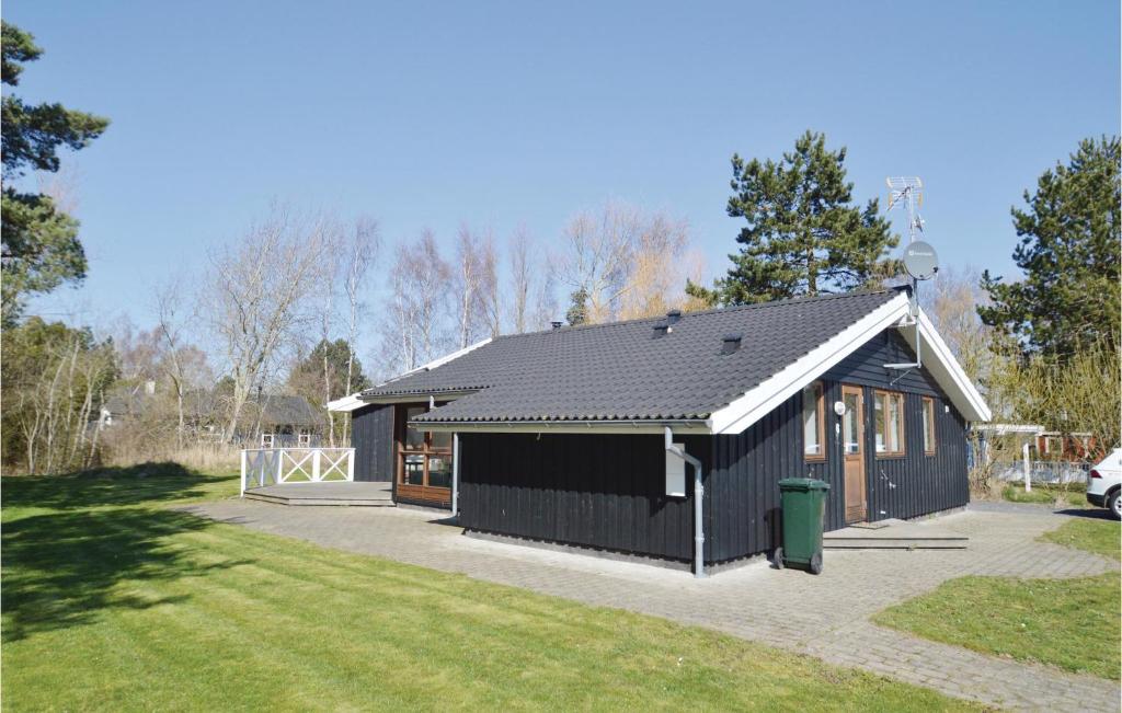 una casa negra con un garaje en un patio en Cozy Home In Rdby With Sauna, en Kramnitse