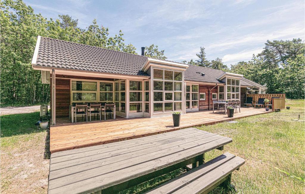 a house with a wooden deck with a table at Rubinsøen Skovhuse in Hasle